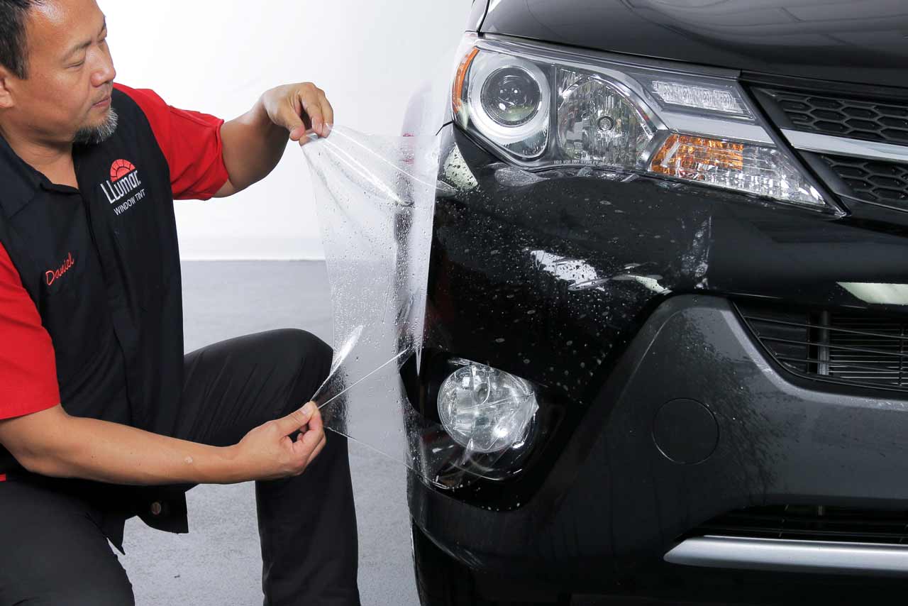 A Technician installing Matte PPF on a black car