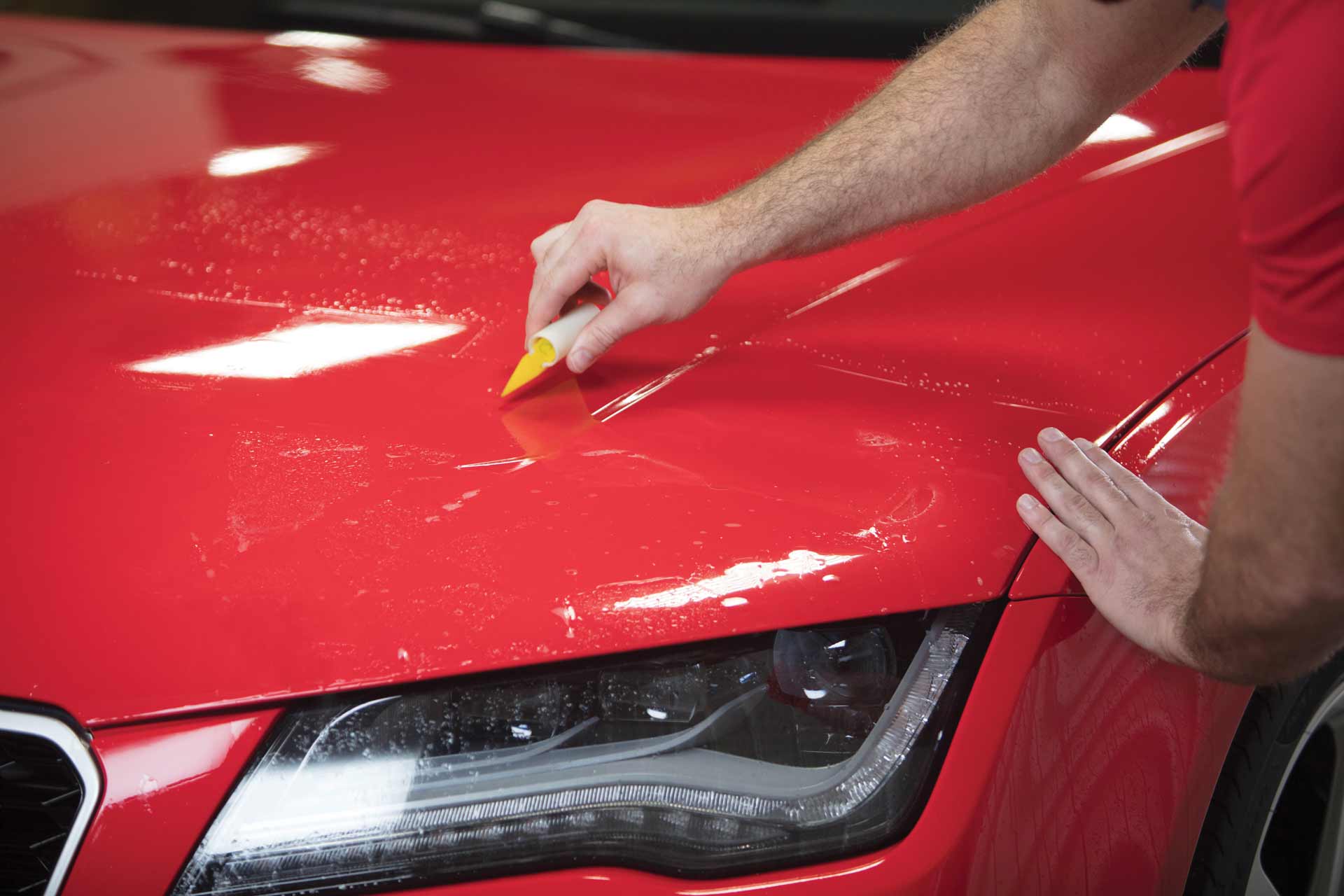 Llumar Valor Paint Protection Film being installed on a red luxury vehicle
